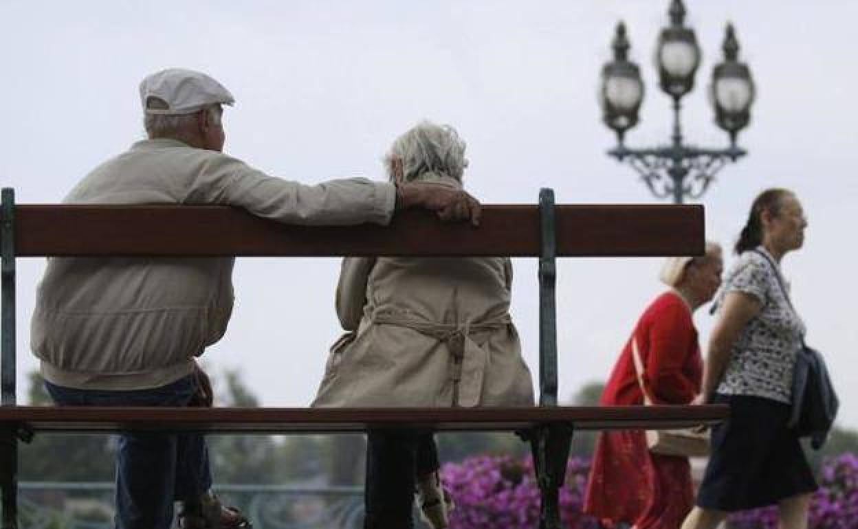 Una pareja de jubilados sentados en un banco. 