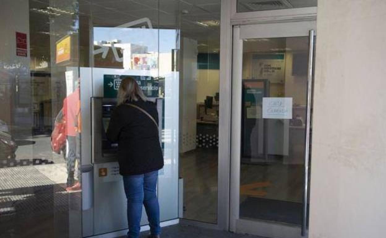 Una mujer saca dinero de un cajero, en una imagen de archivo.