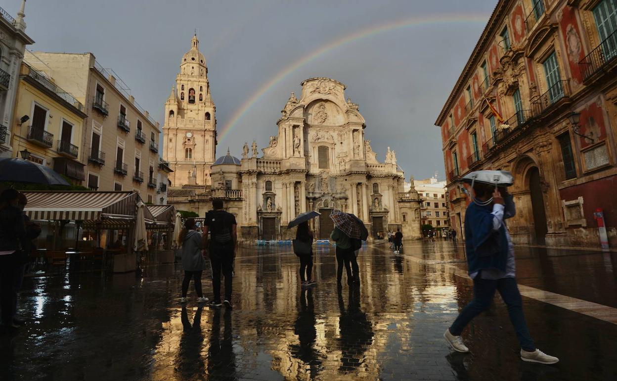 Viandantes en la plaza Cardenal Belluga de Murcia, en un día de lluvia.