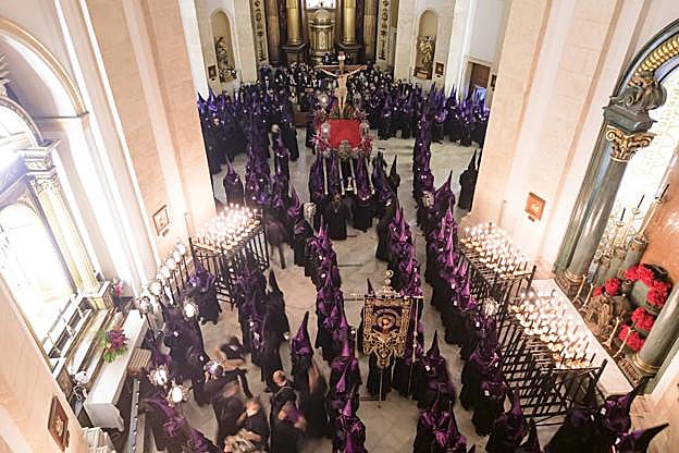 Los nazarenos forman el cortejo en el interior del templo de San Lorenzo ante la talla del Crucificado. 