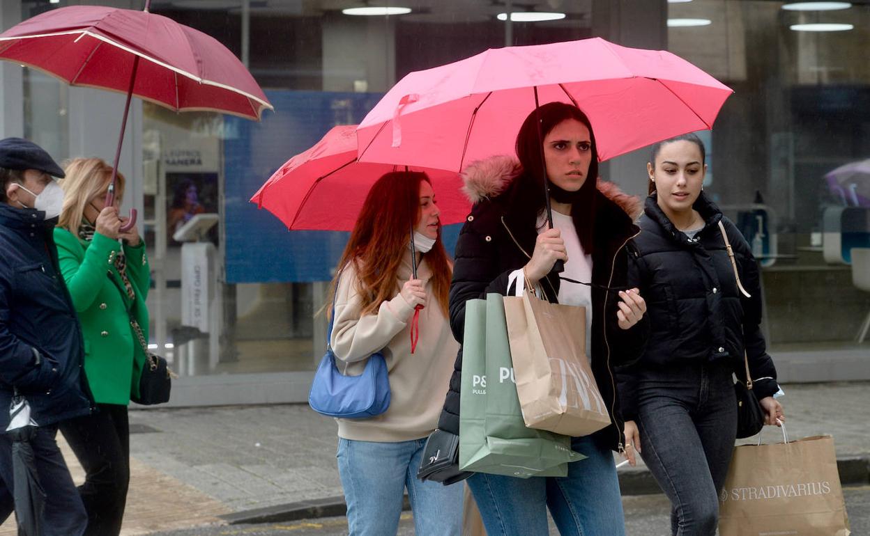 Varios viandantes se protegen de la lluvia, en Murcia, en una foto de archivo.