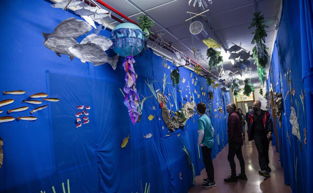 Un grupo de alumnos y profesores en un pasillo adornado con motivos del Mar Menor.