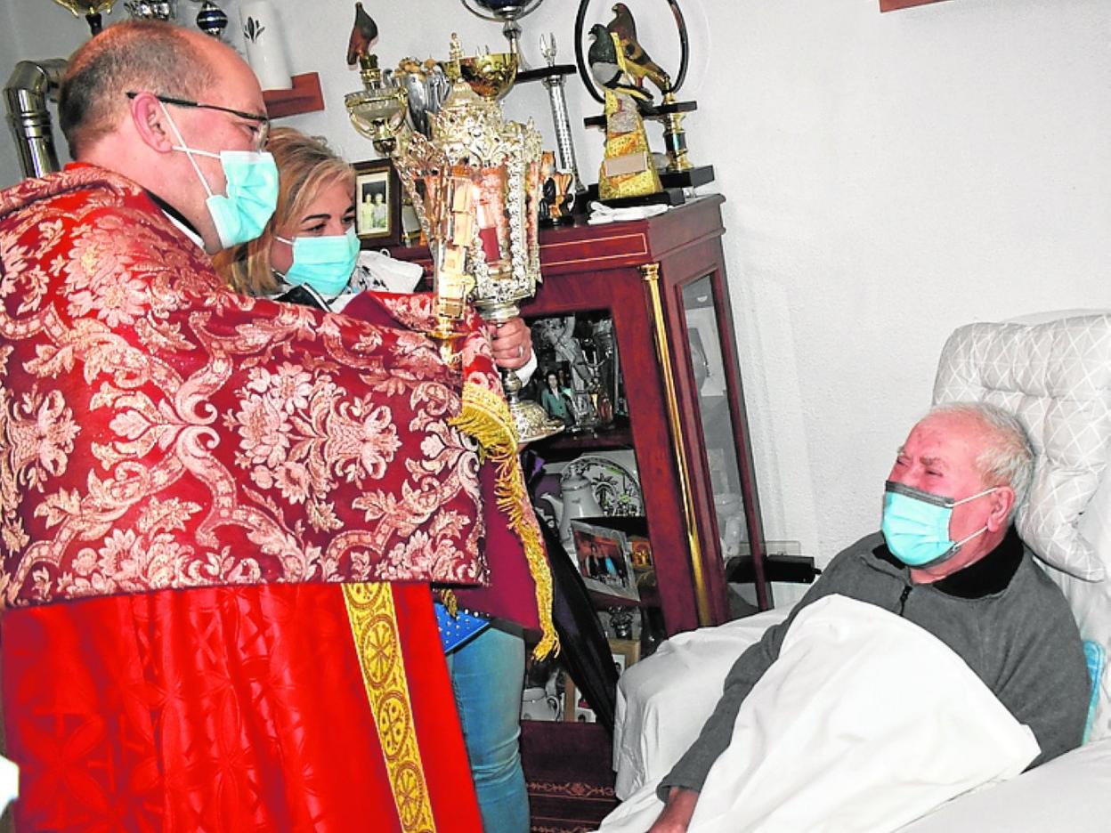 El párroco de El Salvador bendice con la Vera Cruz a un enfermo. 