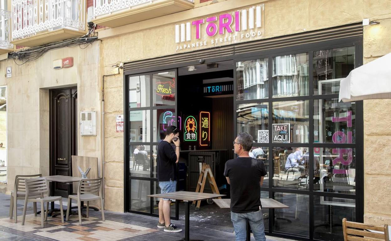 Dos técnicos arreglan la puerta de Tari Sushi rota, ayer. 