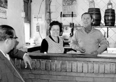 Imagen secundaria 1 - A la izquierda, Inés Lorca y Pepe Flores en la barra del primer local de El Secretario; a la derecha, sus hijas Loren y Conchi muestran fotos del bar que abrió su abuelo en 1916. 