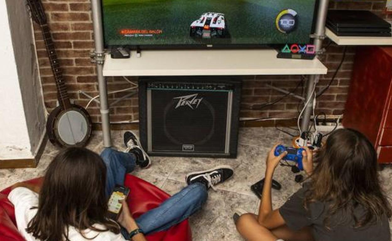 Dos jóvenes juegan al móvil y a la consola.