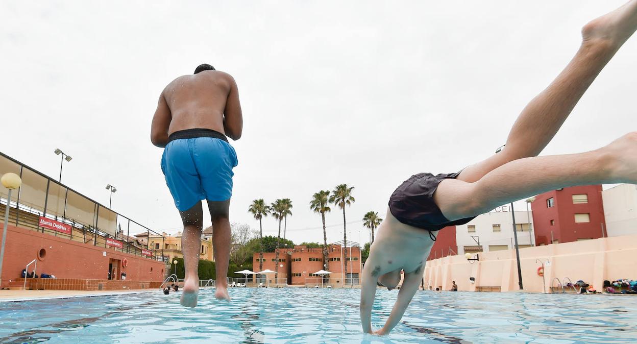 Dos jóvenes se lanzan a la piscina Murcia Parque, ayer, en la apertura de las instalaciones municipales con motivo de la campaña estival. 