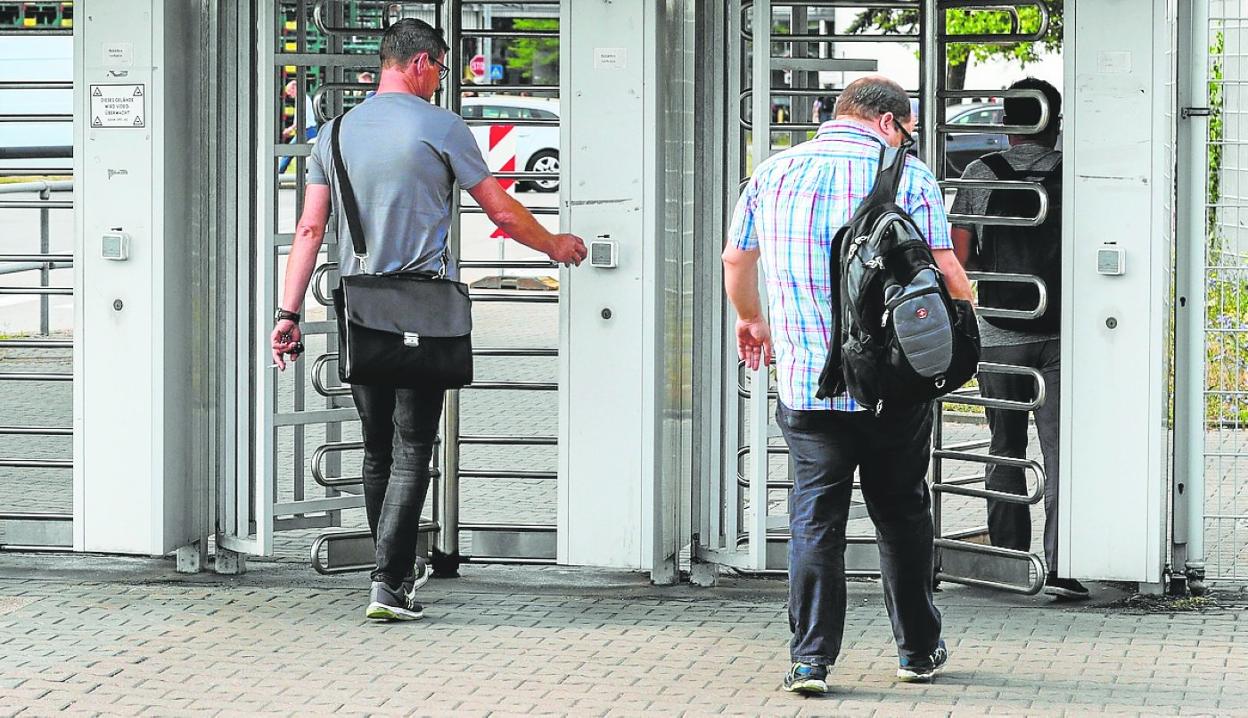 Trabajadores fichando en el acceso a una fábrica. 
