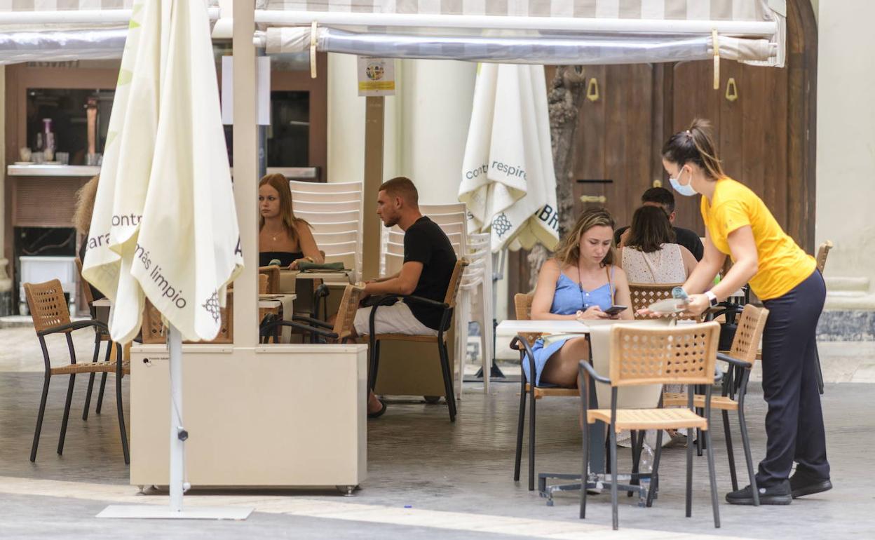 Una camarera atiende a unos clientes en una terraza de Murcia.