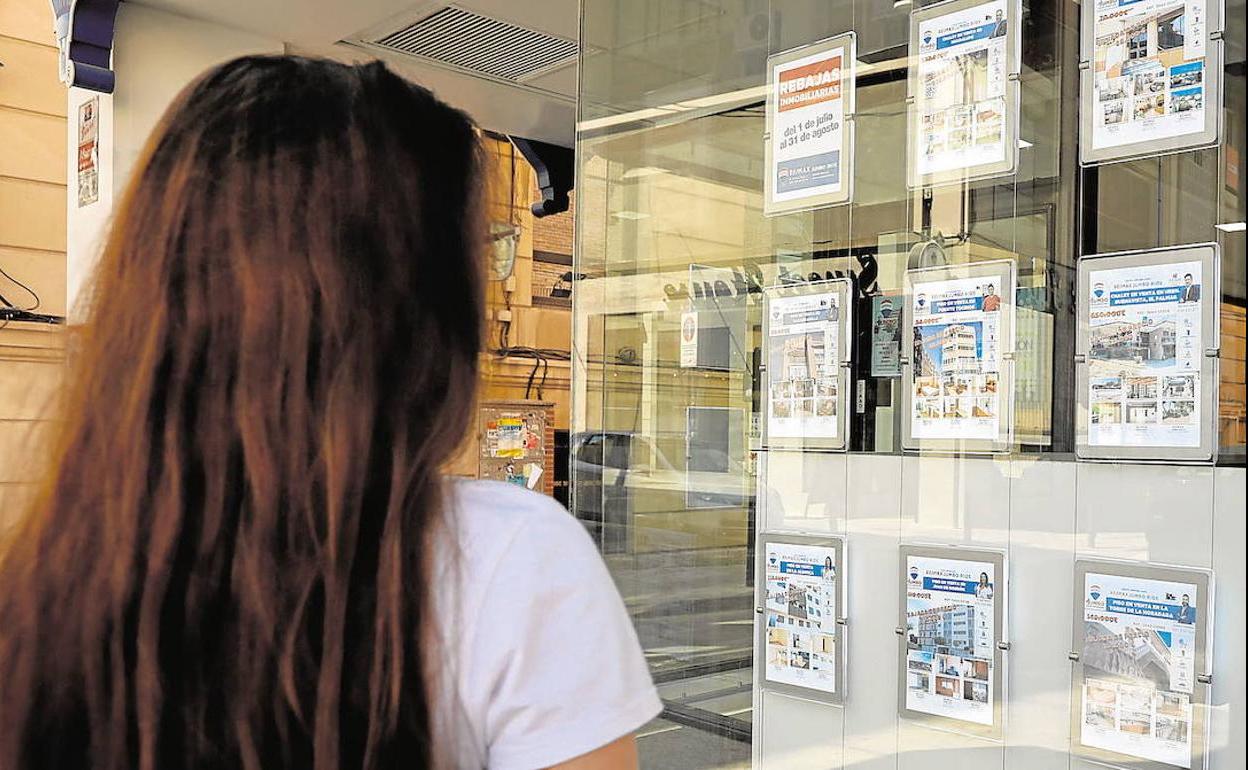 Una mujer observa la oferta de vivienas en alquiler en el escaparate de una oficina inmobiliaria en Murcia, en una imagen de archivo.