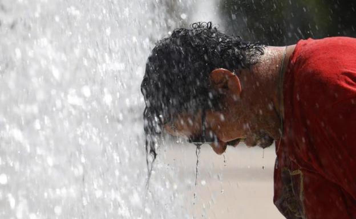 Un hombre se refresca en una fuente. 