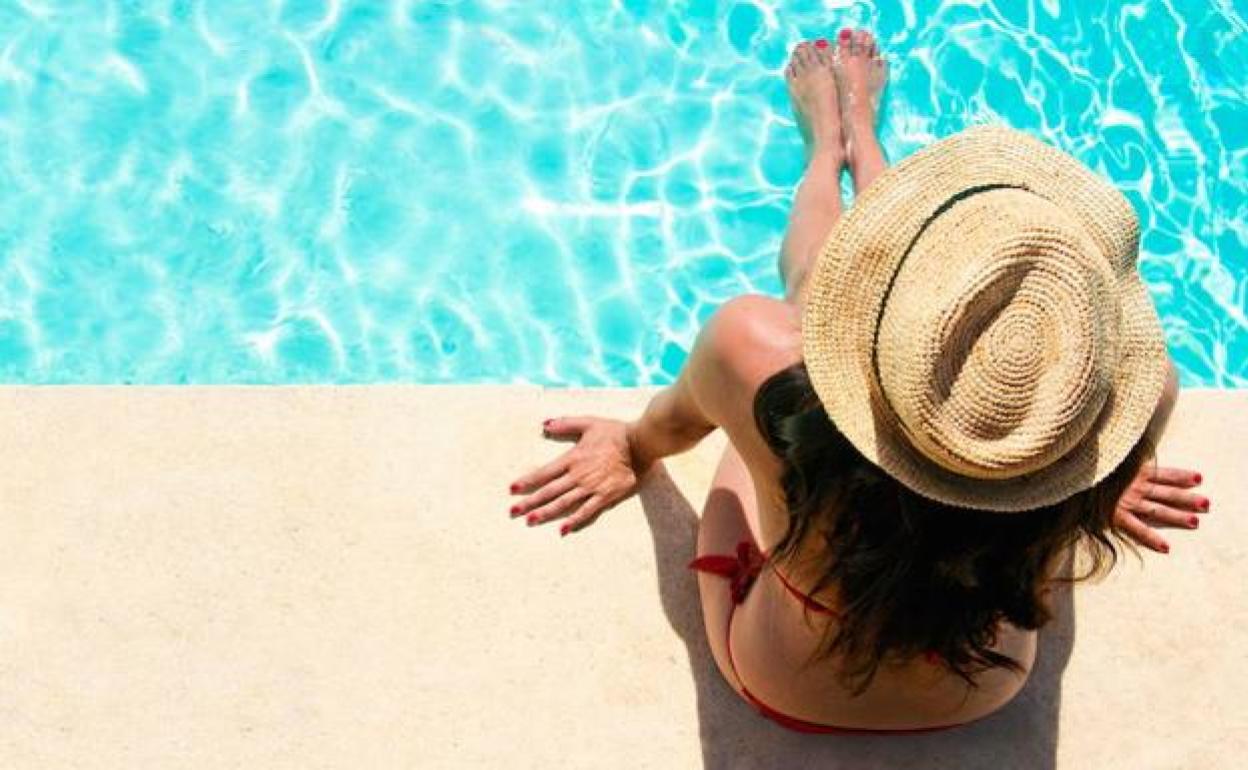 Mujer tomando el sol en una piscina. 