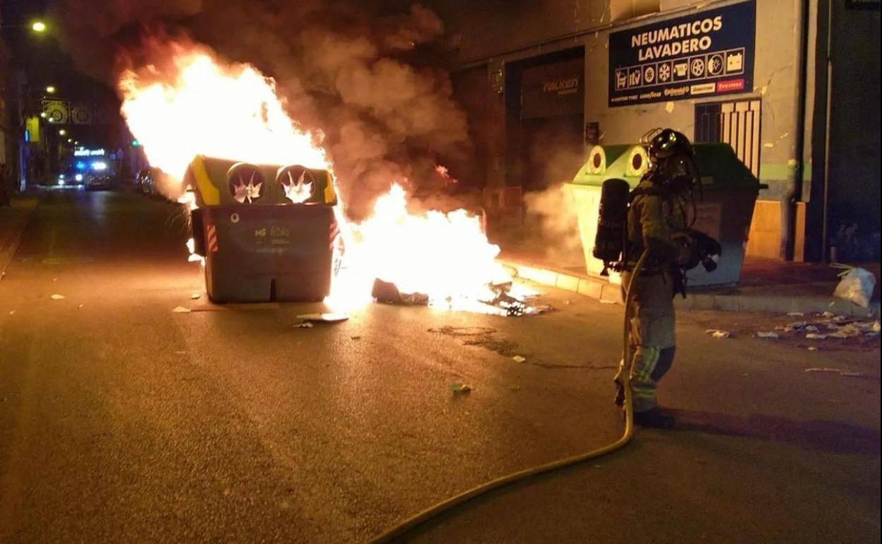 Un bombero intenta sofocar el incendio de un contenedor en La Raya, en la madrugada de este miércoles.