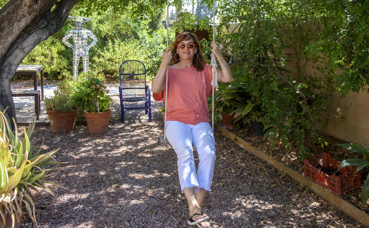 La artista plástica Carmen Baena, en el columpio de su casa, bajo un árbol.