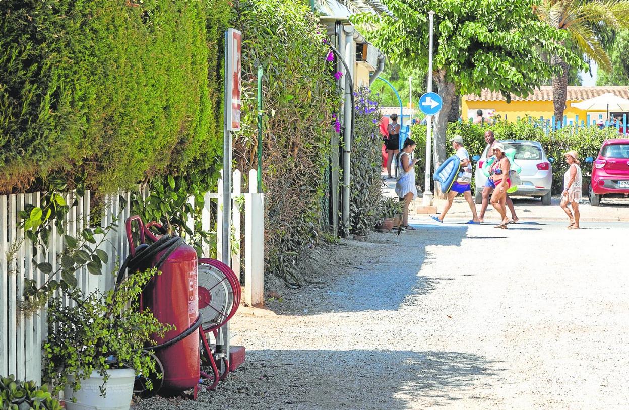 Un grupo de campistas pasean por el recinto de Villas Caravaning. En primer término, un extintor y un carro portamangueras. 