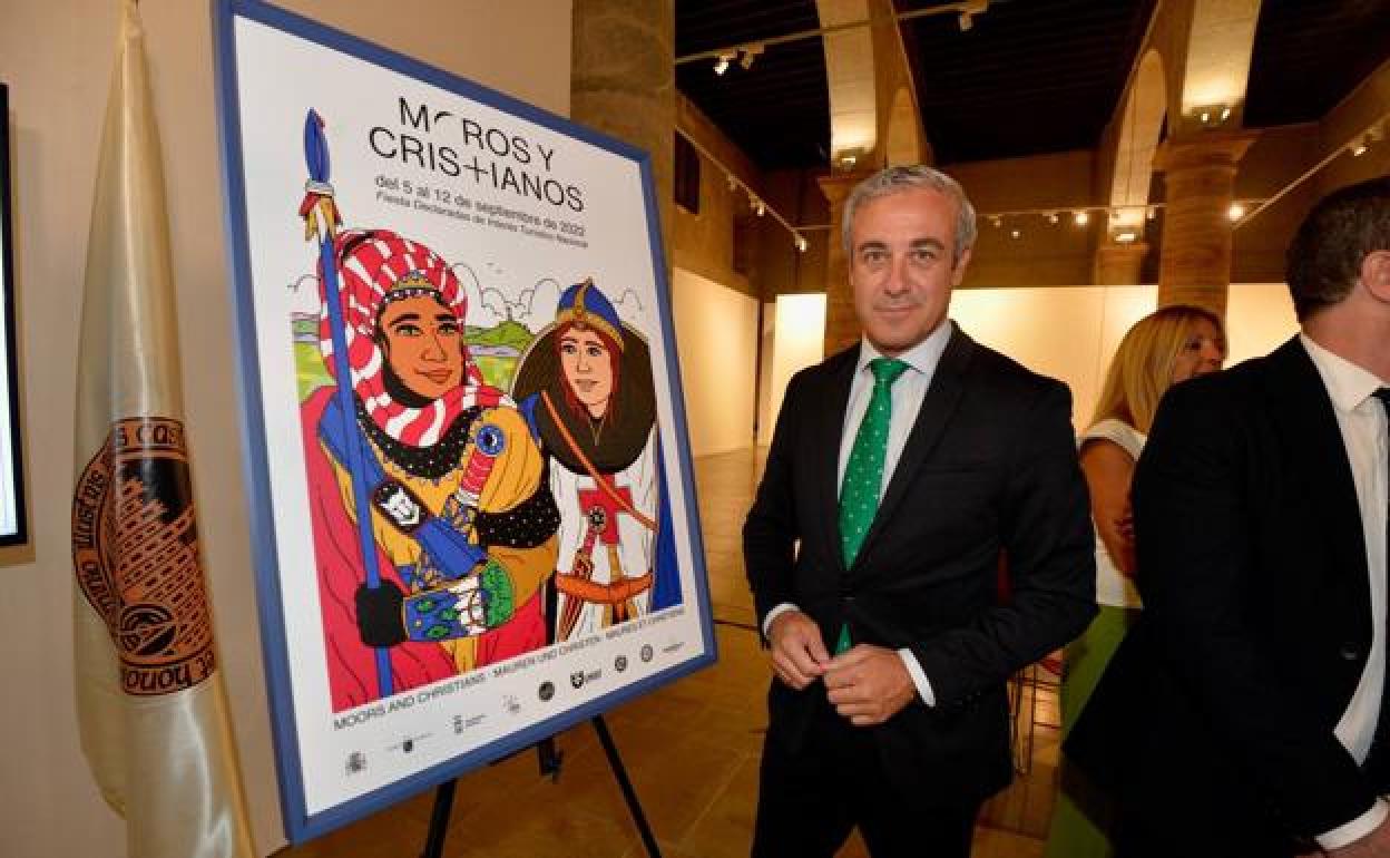 El periodista Antonio Peñarrubia, junto al cartel anunciador de Moros y Cristianos. 