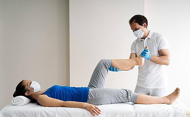 Un fisioterapeuta realiza ejercicios de rehabilitación a una paciente. 