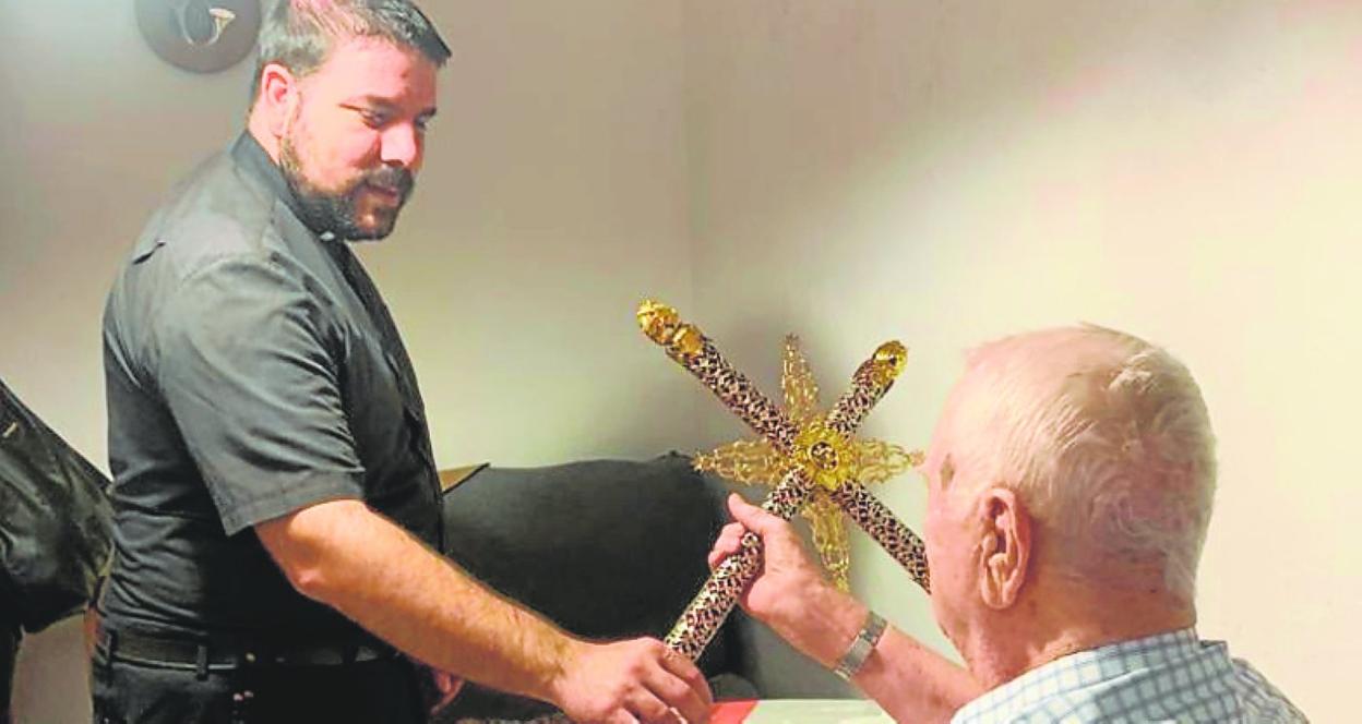 El sacerdote de Santo Domingo muestra la cruz a un vecino. 