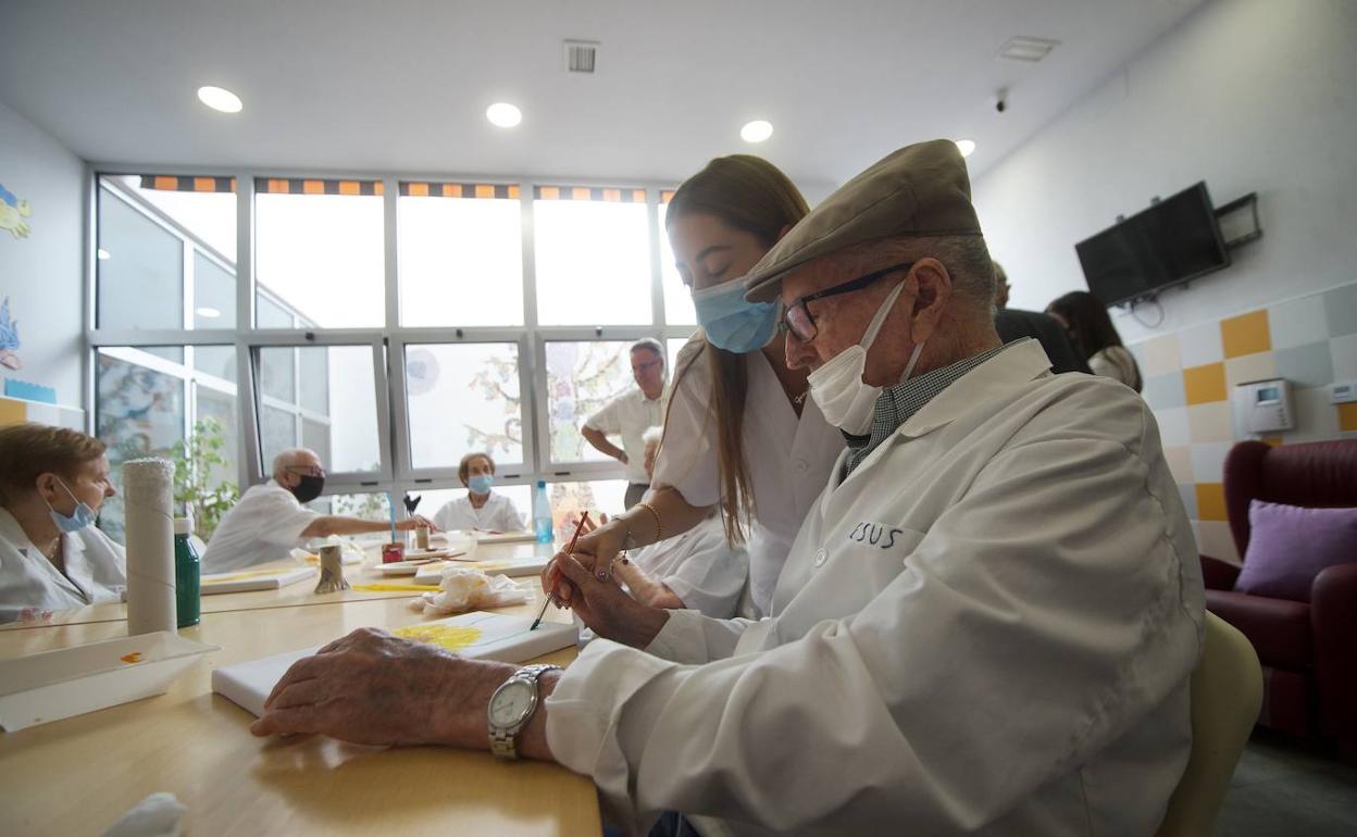 Una sanitaria acompaña a un usuario del centro de estancias diurnas de Afade en Alcantarilla. 