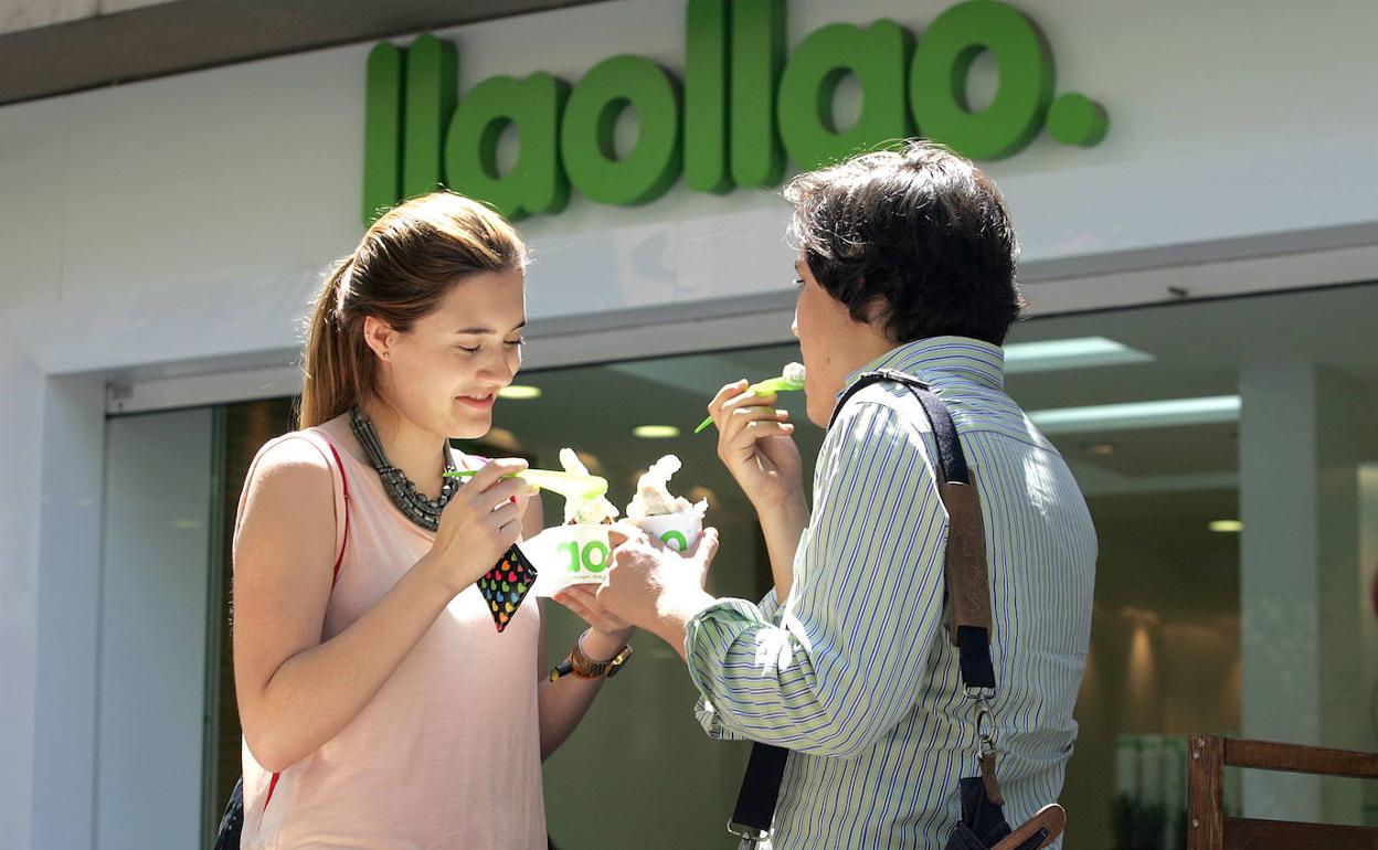 Una pareja toma un yogur en la puerta de un establecimiento de llaollao. 