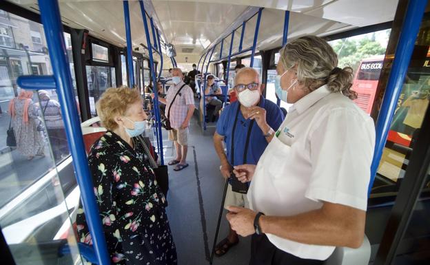 El conductor de un autobús explica, este jueves, a dos pasajeros la gratuidad del billete del transporte público en Murcia. 