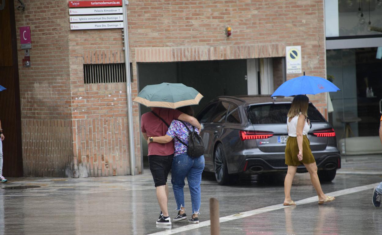 Varias personas se protegen de las lluvias en Murcia.