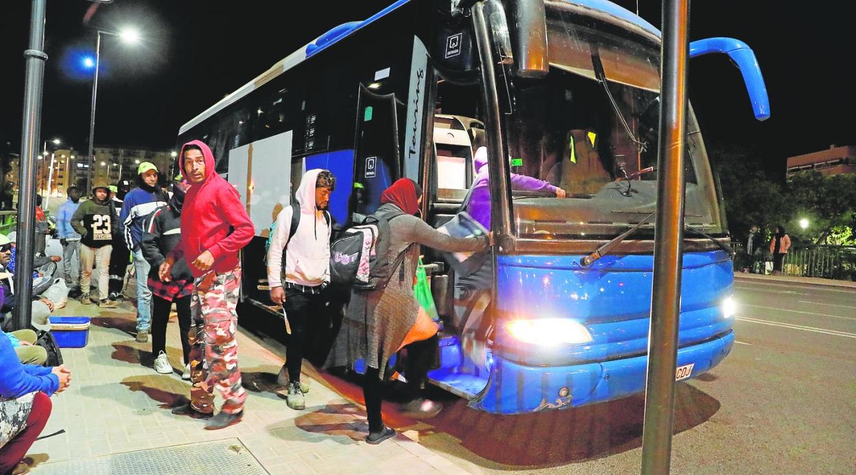 Jornaleros se suben a un autobús, a las 4.30 de la madrugada en el puente de San Diego, que los llevará a trabajar al campo, el miércoles. 