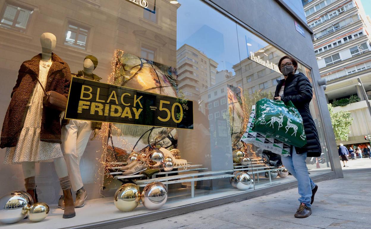 Una viandante pasa junto a un cartel promocional del Black Friday, el año pasado. en Murcia