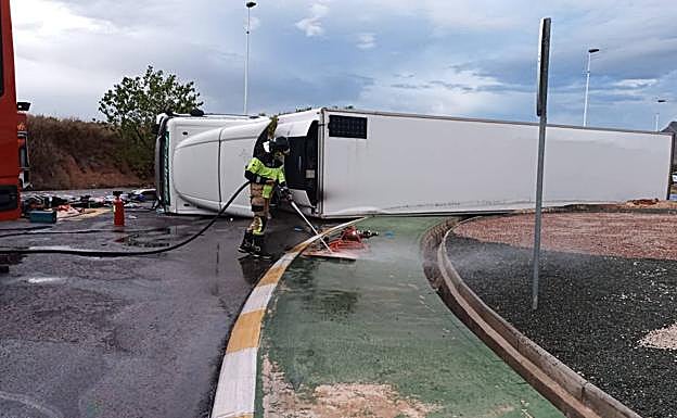 Un bombero limpia el combustible derramado de la calzada y la rotonda. 