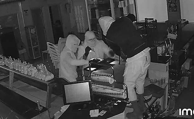 Los asaltantes, intentando forzar la caja de cobro del establecimiento. 