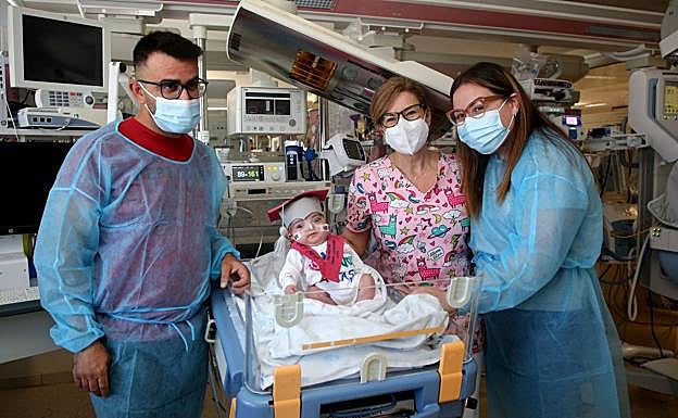 Julieta, disfrazada de graduada, con sus padres, José Illán y Rosa María Graña, y la enfermera Fátima Cervilla, ayer en la UCI neonatal de La Arrixaca.