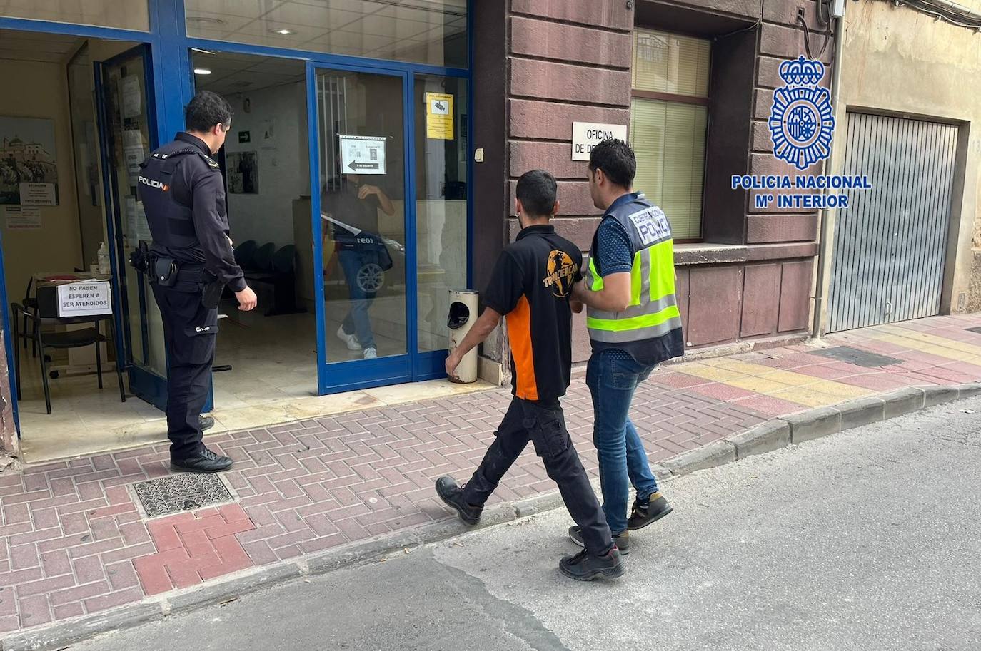 Dos agentes acompañan a uno de los detenidos.