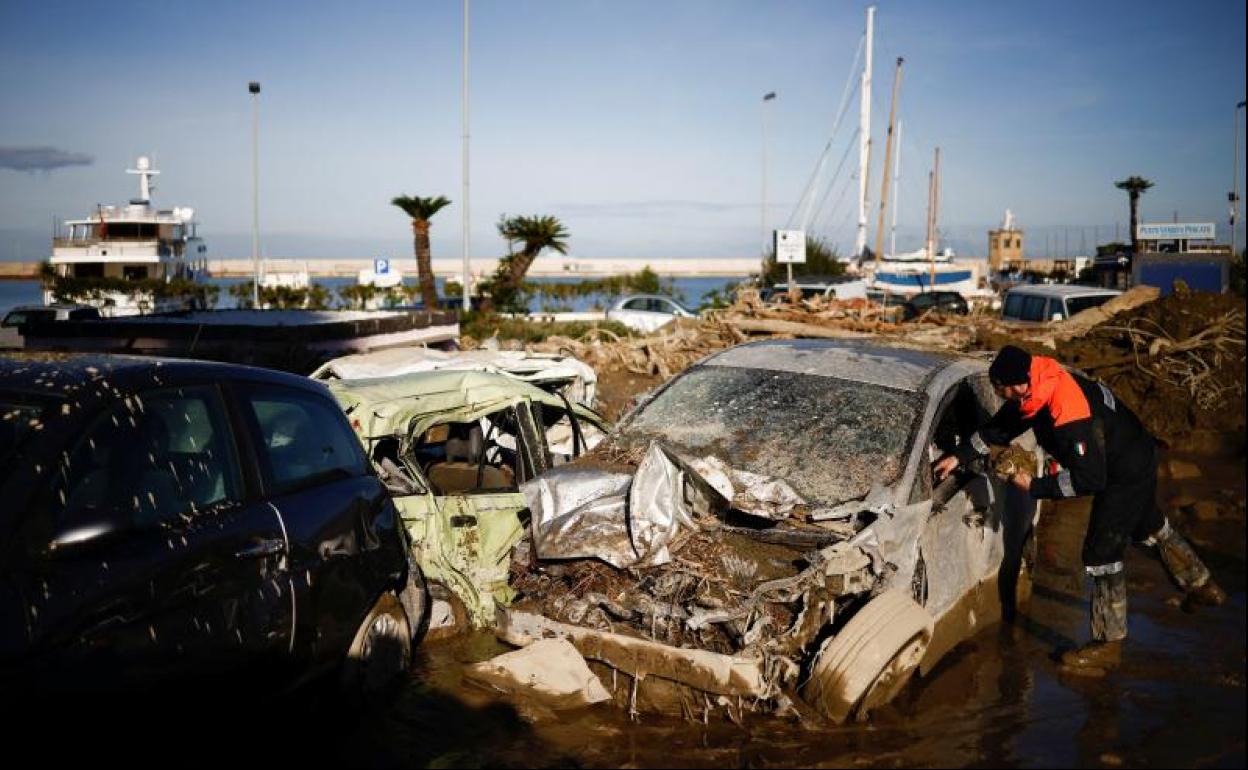 Un miembro de la Guardia Costera busca documentos dentro de un coche destruido por el alud en la isla de Ischia. 