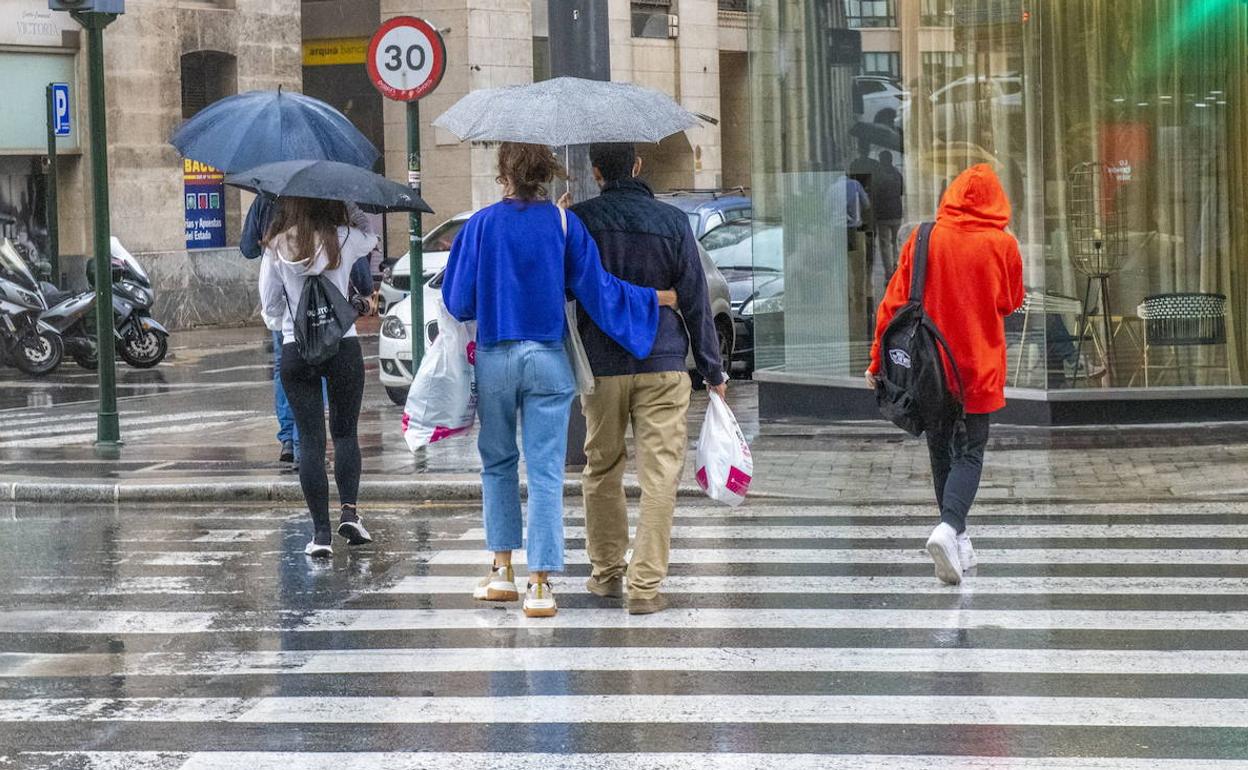 Varias personas pasean bajo la lluvia en Murcia, en una imagen de archivo.