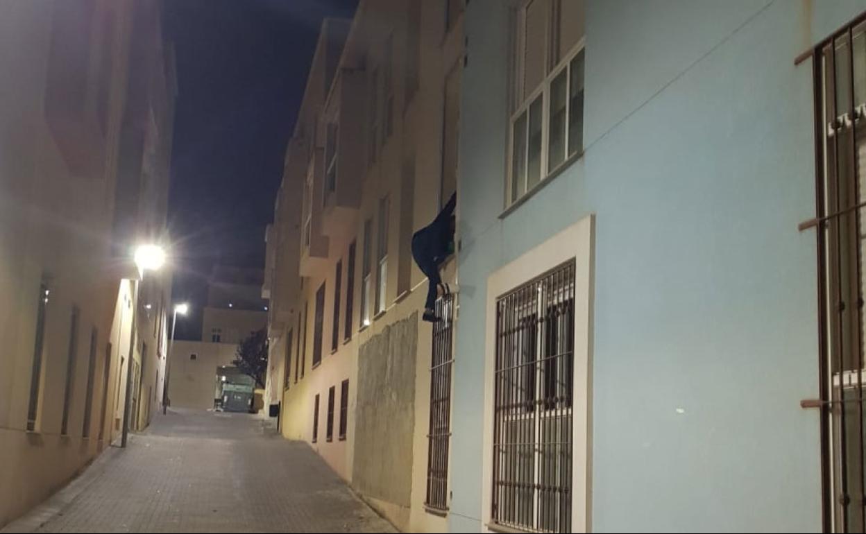 Un okupa entra a un edificio trepando por una ventana. 