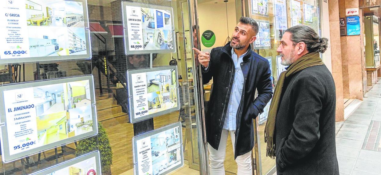 José Liarte muestra a un cliente uno de los carteles digitales que tiene en el escaparate de su inmobiliaria, ubicada en la calle Santa Florentina. 