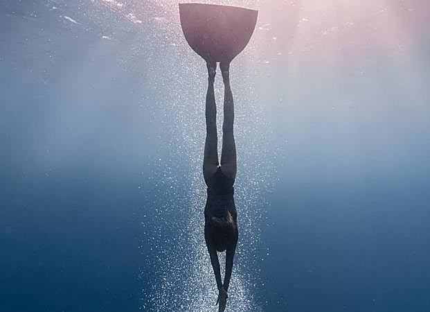 La apneísta Laia Sopeña se sumerge en el agua con su monoaleta. 