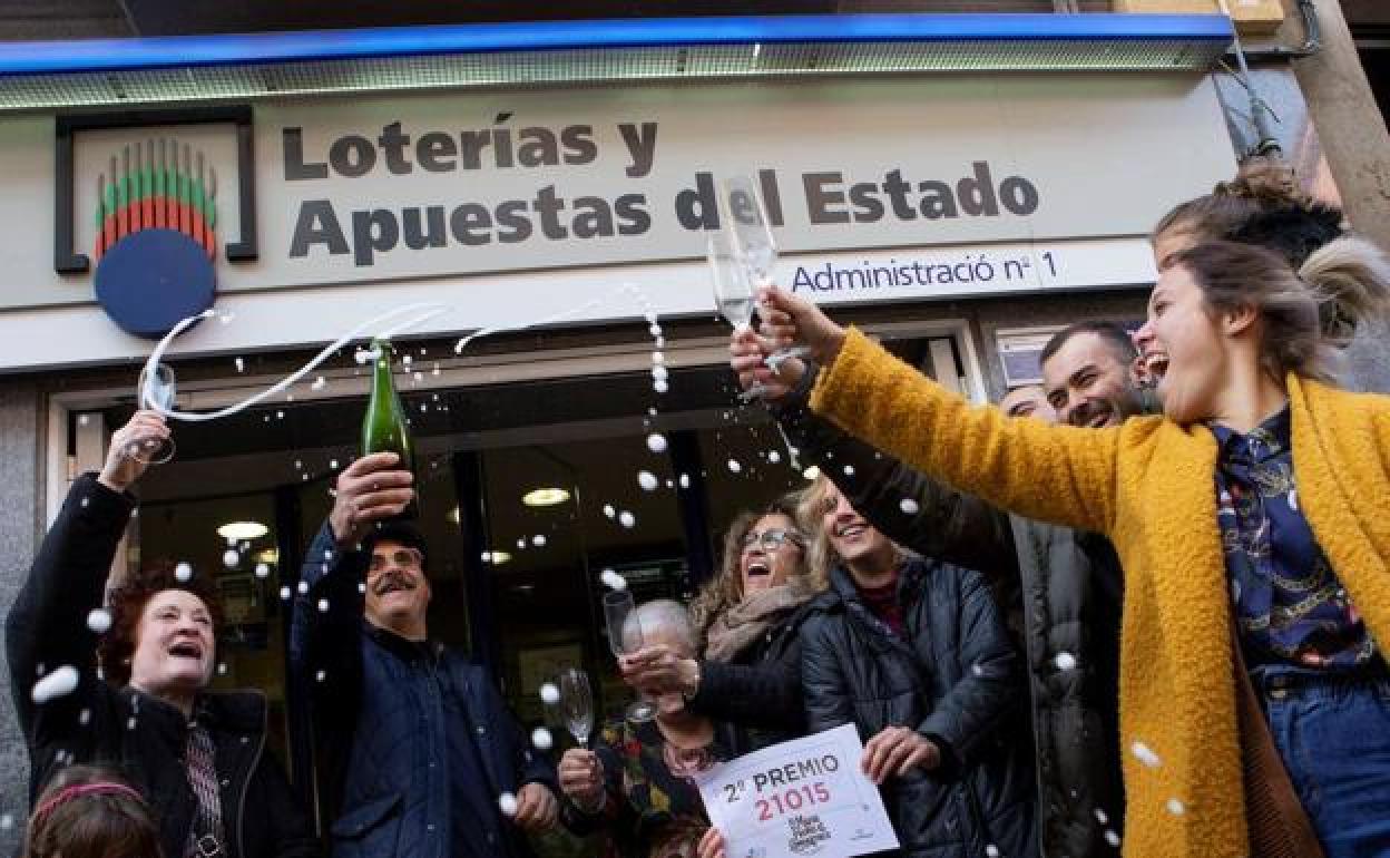 Un grupo de ganadores de un segundo premio celebra su buena suerte frente a una administración de lotería.