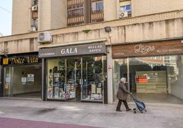 Una señora pasa ante dos tiendas recientemente cerradas en el centro de Murcia.