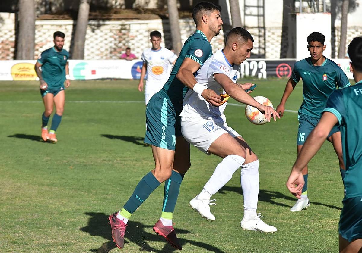 Piqueras controla el balón con el pecho presionado por un defensa.