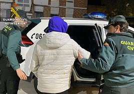 Dos guardias civiles acompañan al detenido al coche.