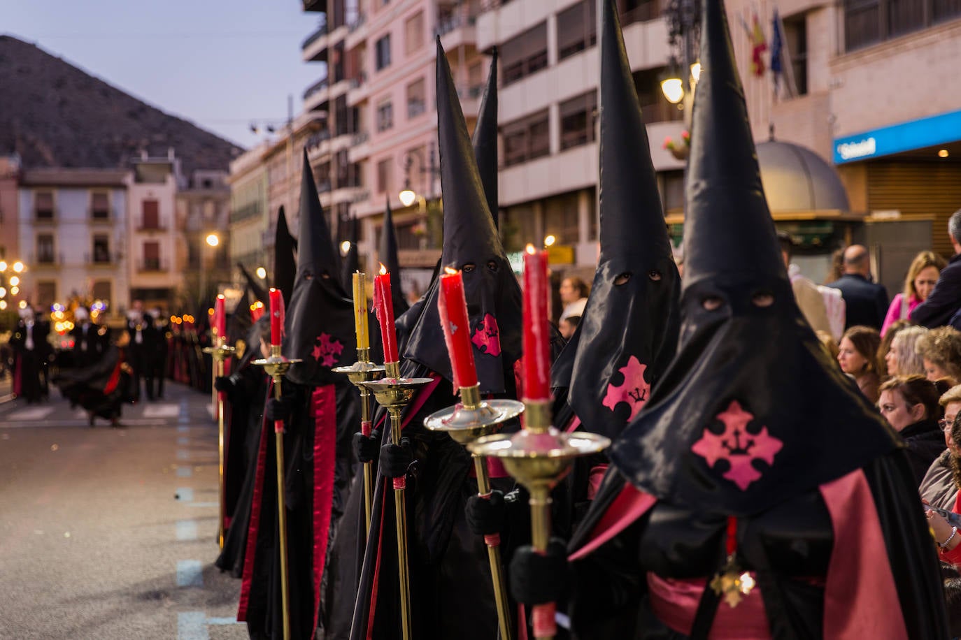 Estandartes y nazarenos de Nestro Padre Jesús de la Caída, la imagen titular de la Cofradía, llevan el negro corporativo con listas rojas