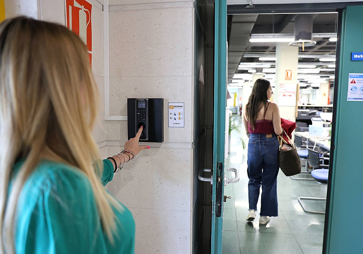 Una trabajadora introduce el dedo índice en el lector de huella digital antes de iniciar su jornada laboral.