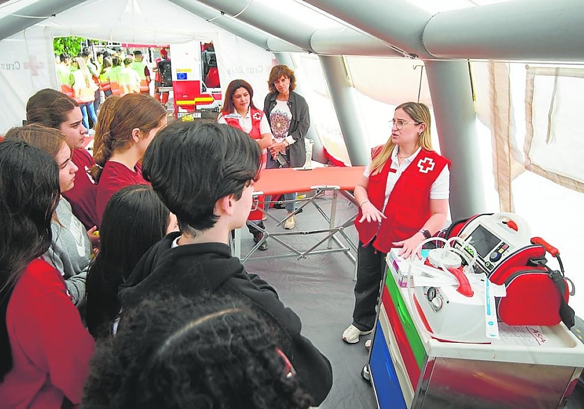 Una voluntaria de Cruz Roja muestra a varios jóvenes material sanitario de la ONG, ayer en Murcia.