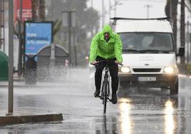 Un ciclista y un vehículo circulando durante una tormenta, en una imagen de archivo.