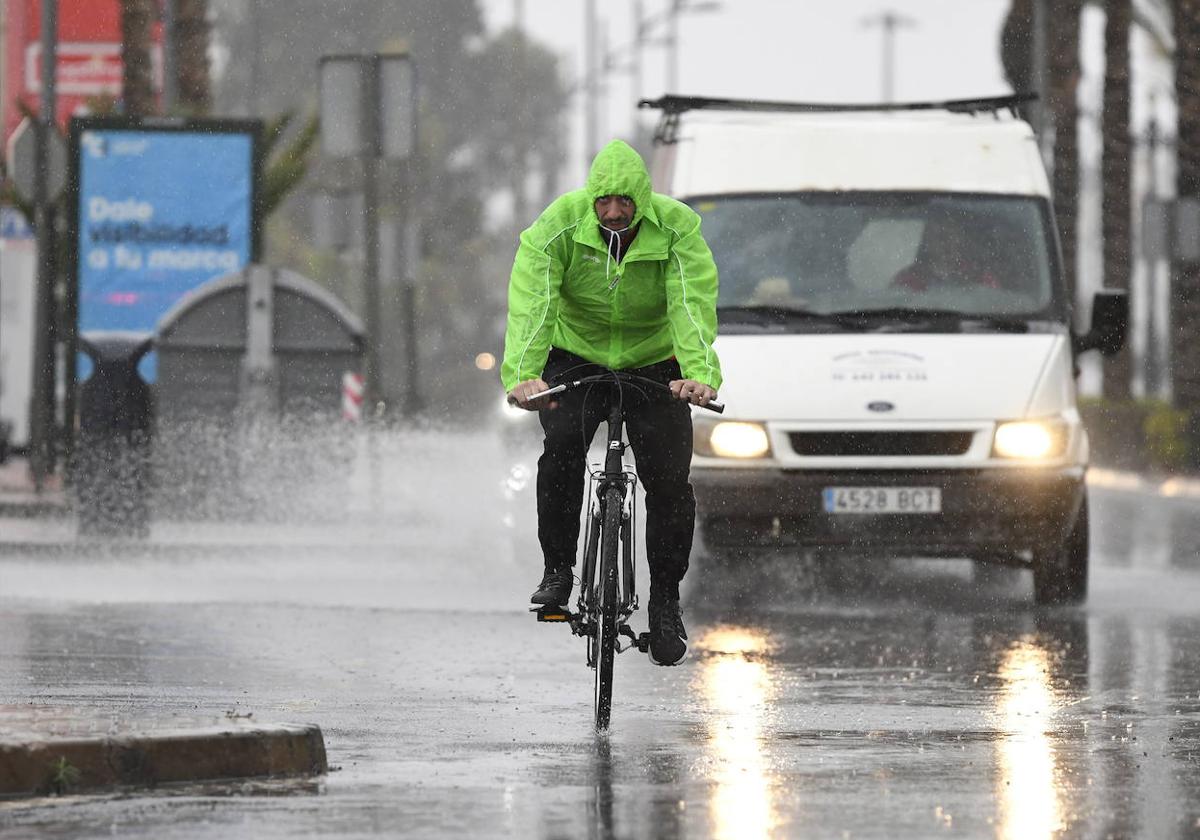 Un ciclista y un vehículo circulando durante una tormenta, en una imagen de archivo.