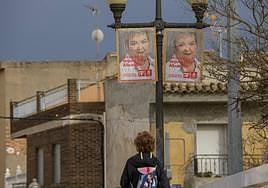 Una vecina de Albudeite pasa junto a los carteles de Isabel D. Peñalver, detenida por presunta compra de votos.