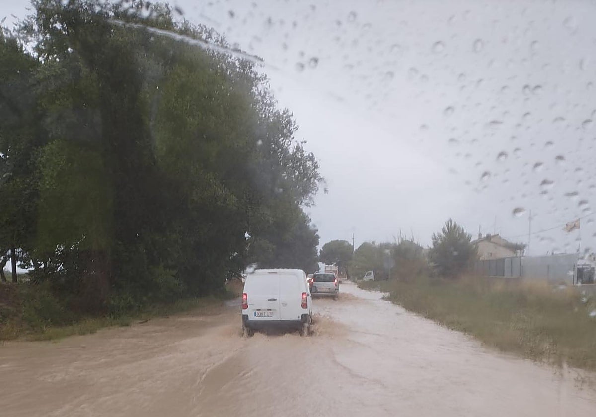 Vehículos circulan por un camino anegado por la lluvia.
