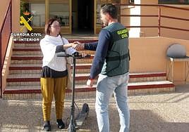 Un agente de la Guardia Civil devuelve uno de los patinetes sustraídos a su dueña.