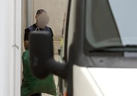 Un policía nacional traslada una bolsa con cogollos de 'maría' a una furgoneta.